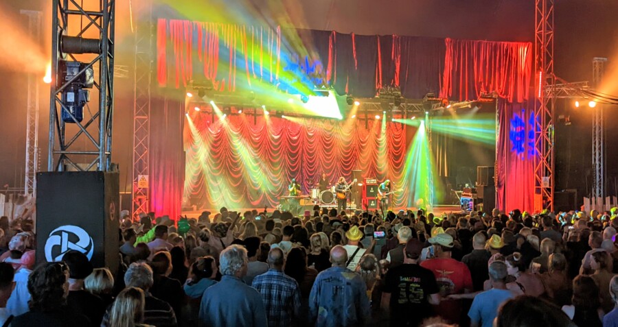 crowd and multicolour lights in front of a stage where the magic numbers are performing